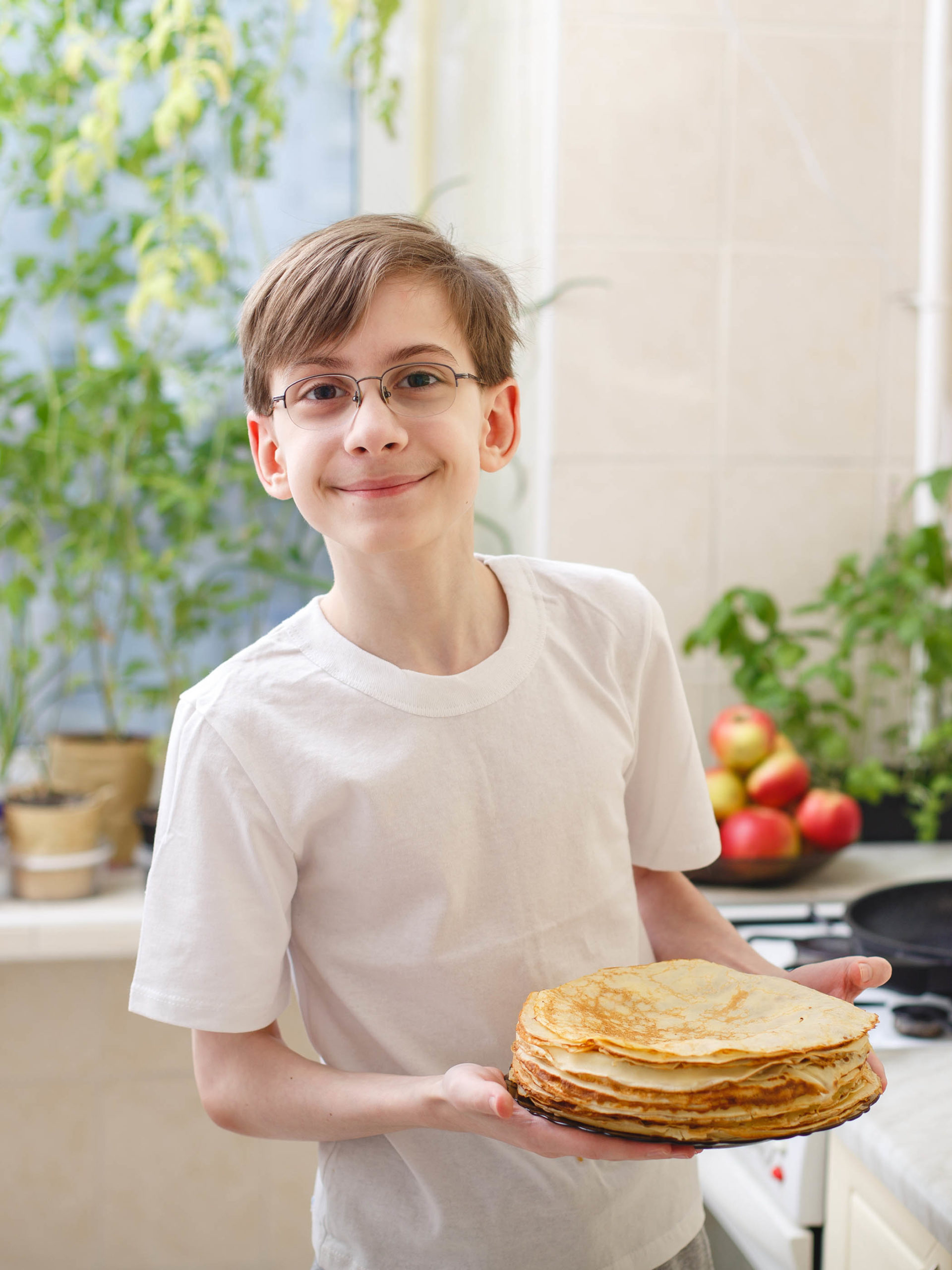 teen boy fries gluten-free pancakes in the kitchen