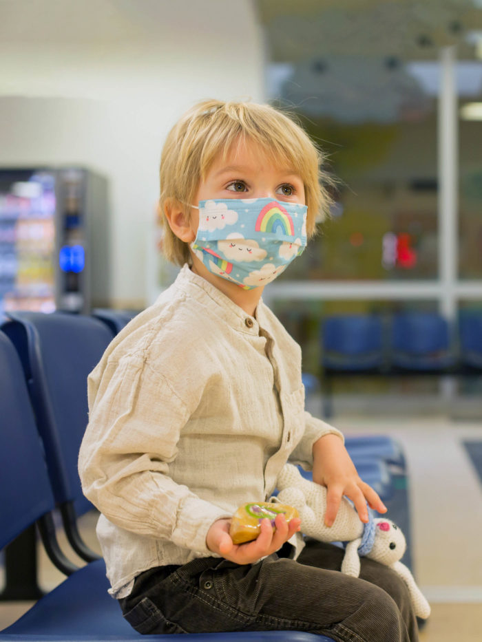 young boy wearing mask waiting in pharmacy for medication