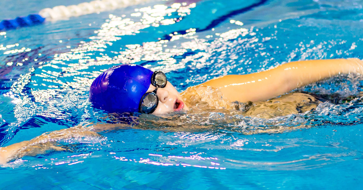 boy in swimming cap wearing goggles in swimming pool