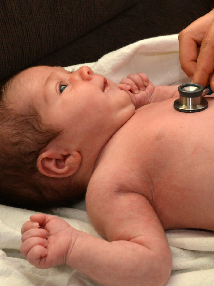 Doctor checks newborn baby heart beat with stethoscope