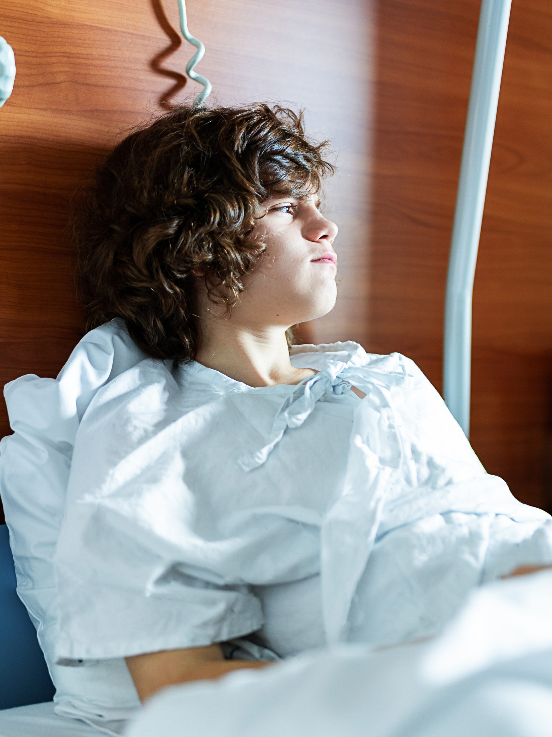 teen boy sitting in a hospital bed looking distraught