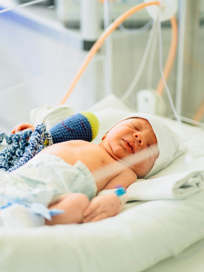 Two-day-old newborn baby boy in intensive care unit in a medical incubator
