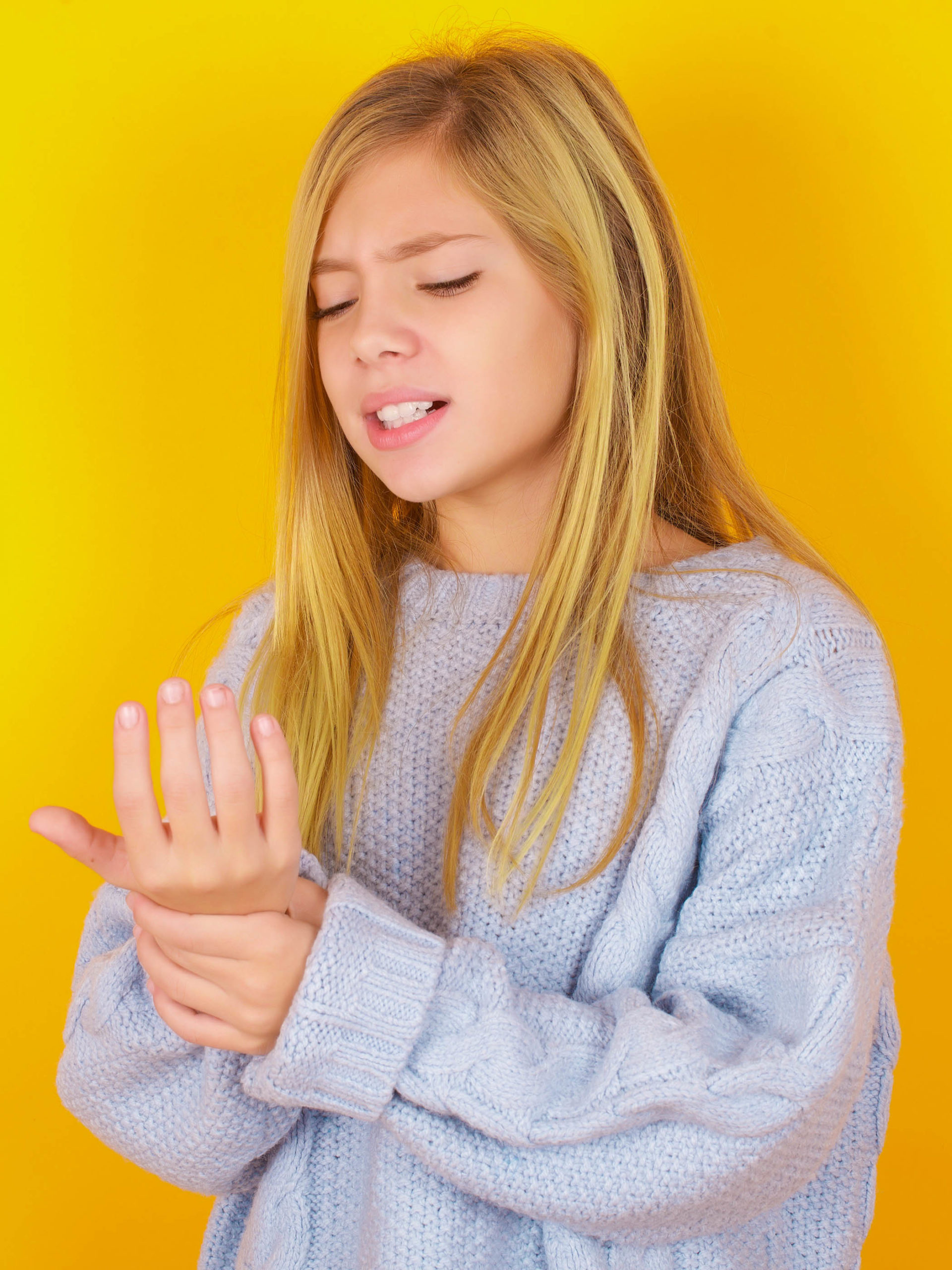 girl suffering from pain on hands and fingers