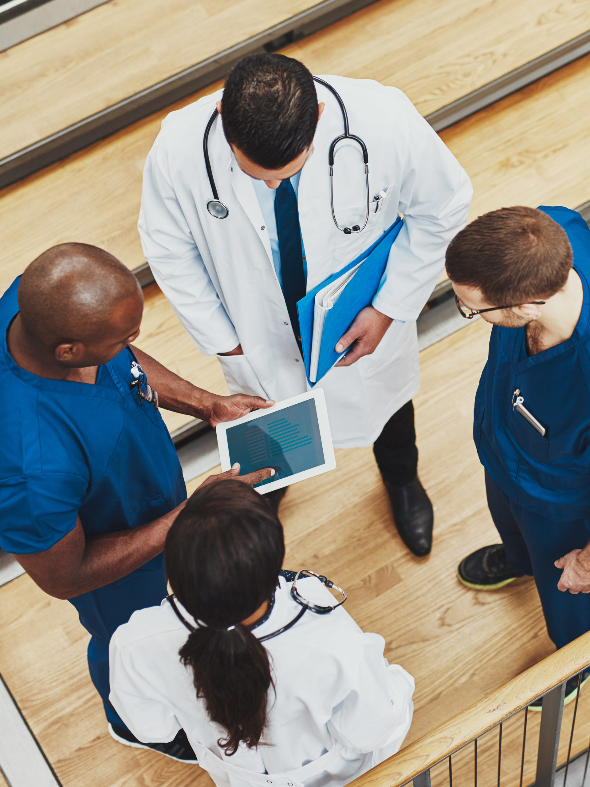 medical team having a discussion as they stand grouped together around a tablet