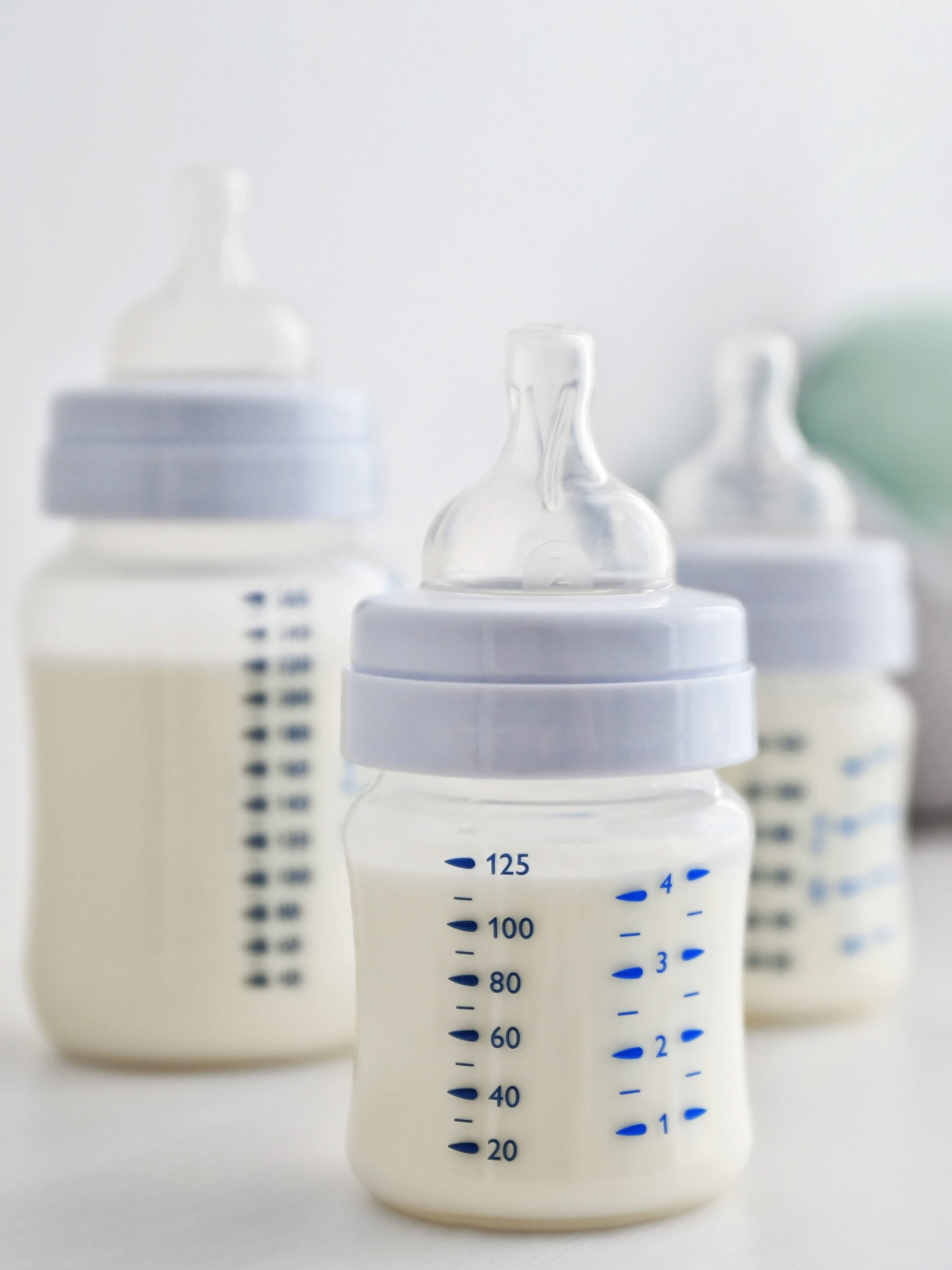 Baby milk bottles and toys on white background