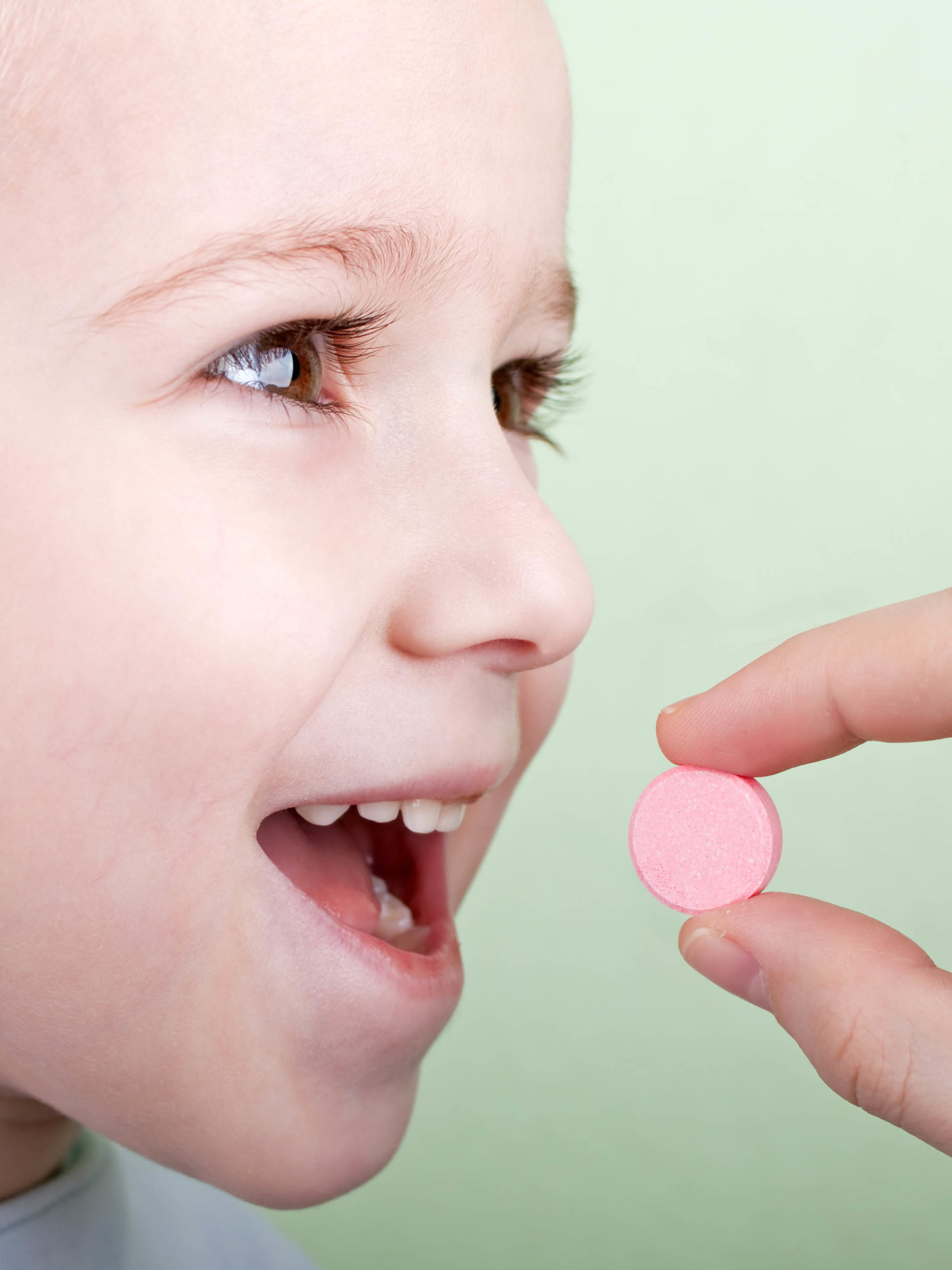 Human hand giving child chewable tablet medication