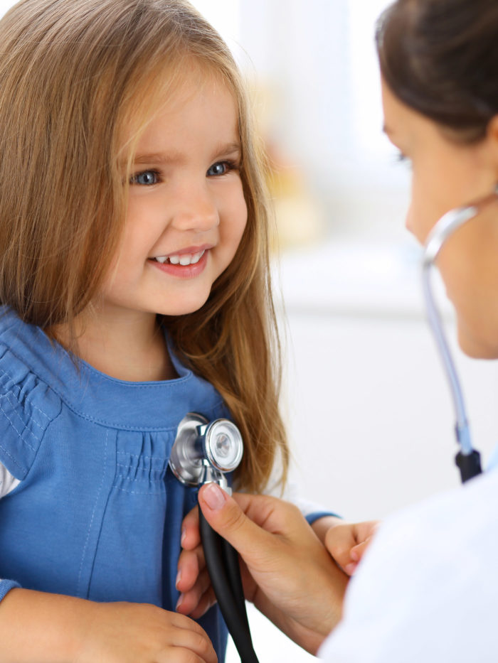 Female doctor examining a little girl with stethoscope