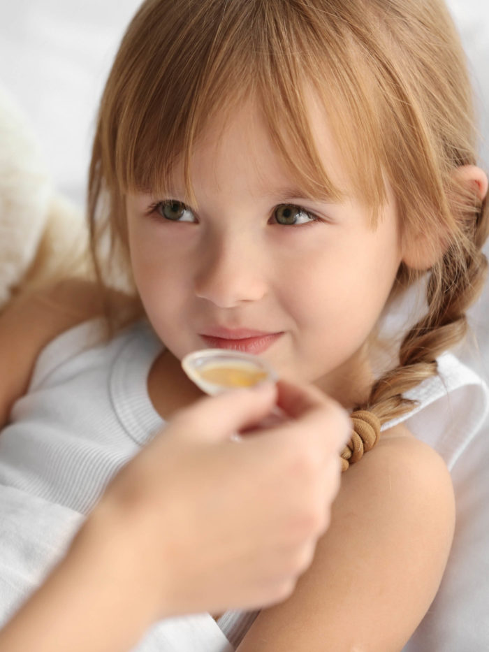 mom giving medicine on a spoon to school aged girl