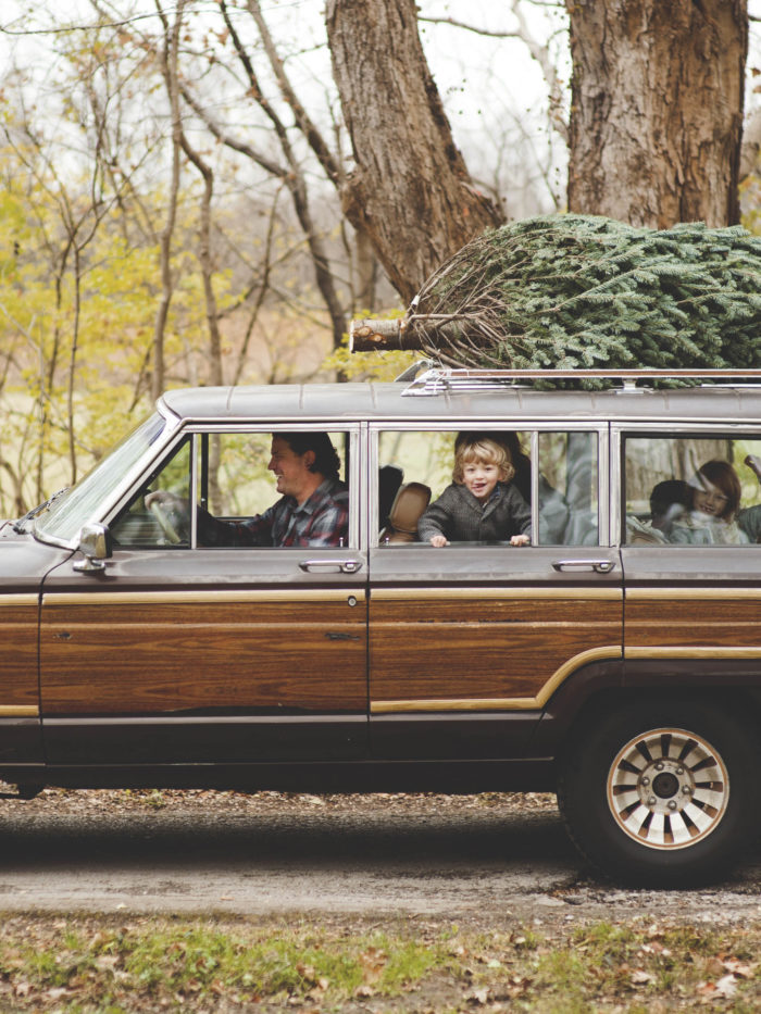 Family getting a Christmas tree in a vintage car