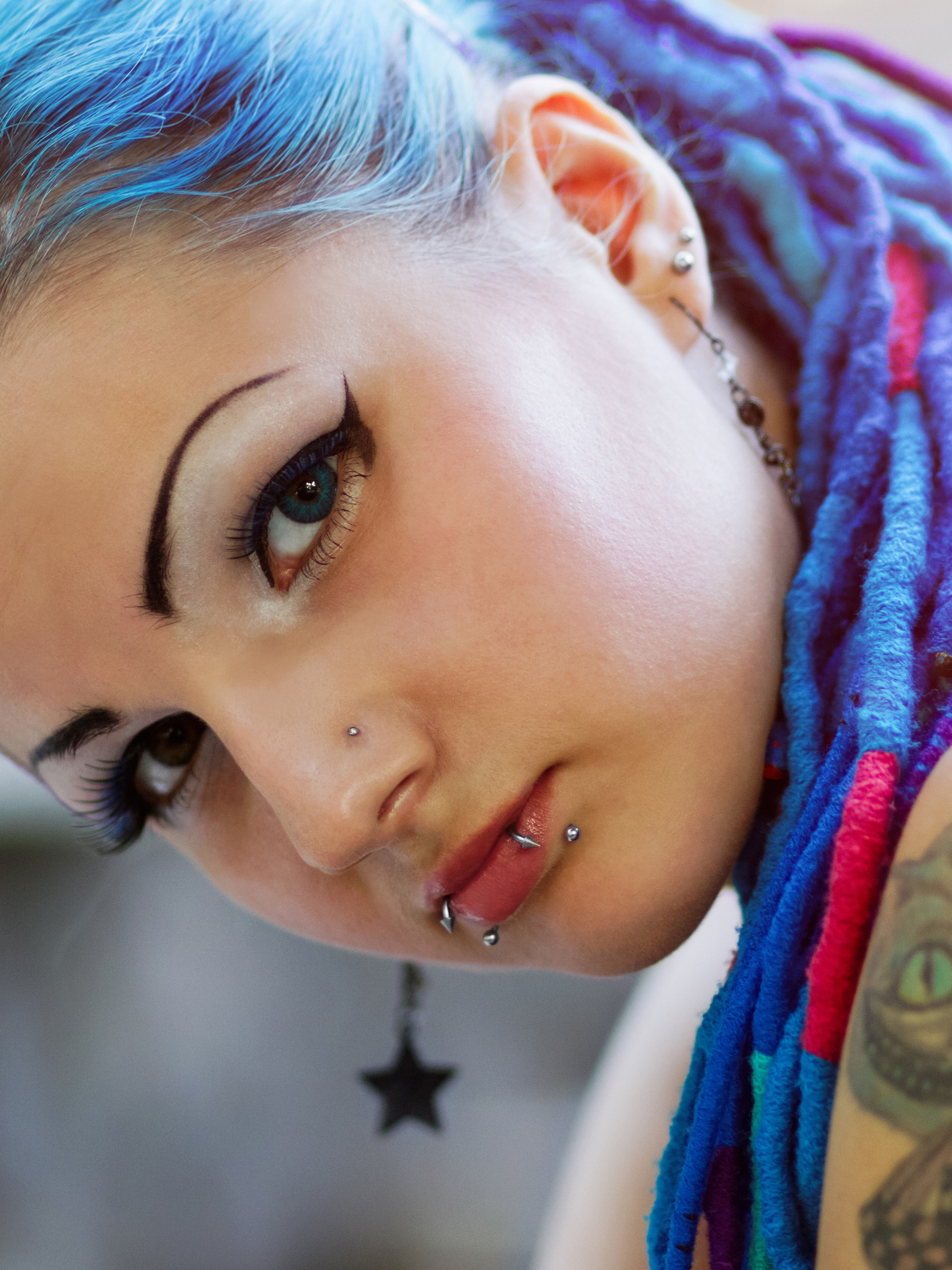 teen girl with blue dreads, lip piercings and tattoo