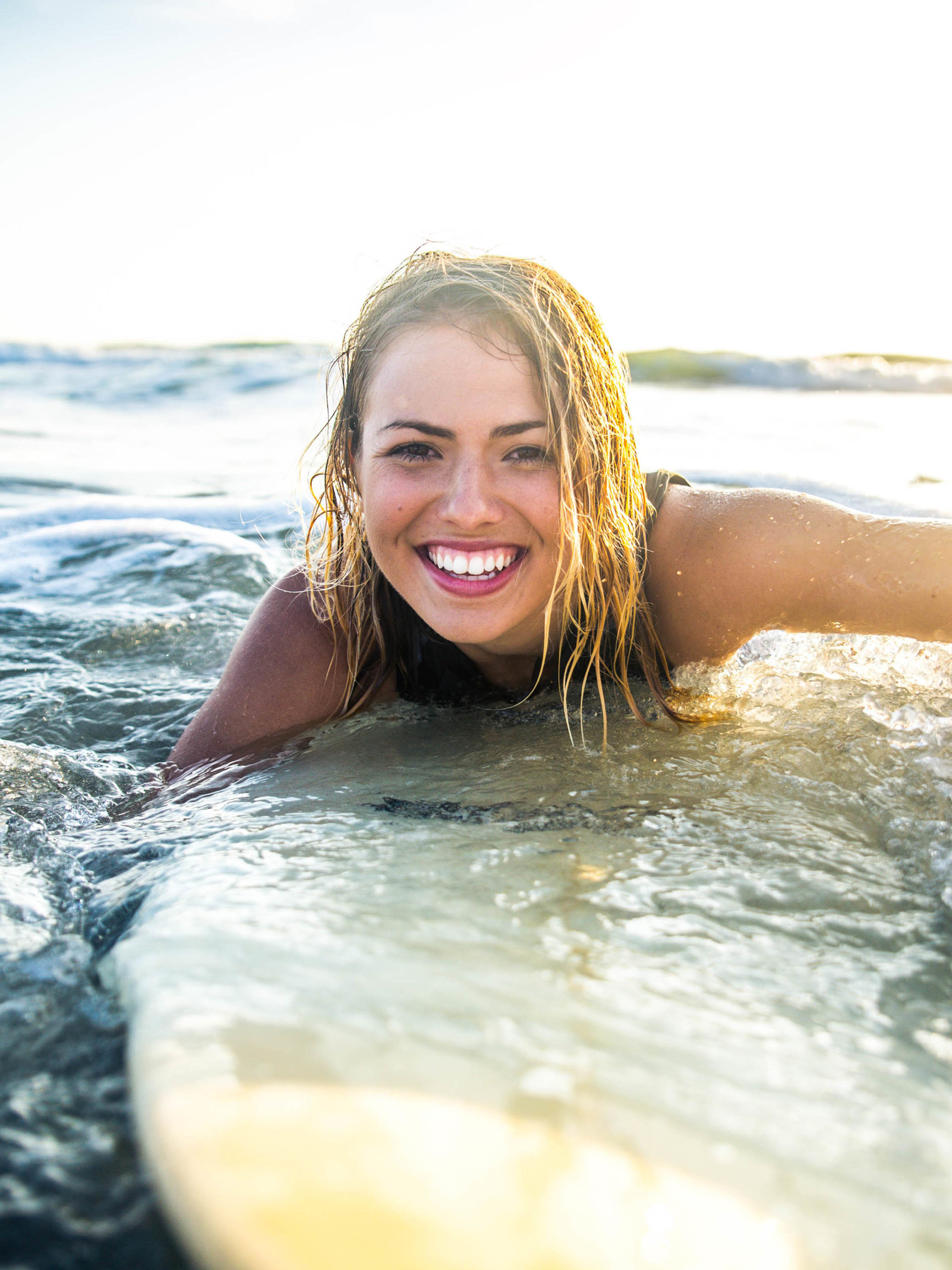portrait of young woman on surfboard in the ocean