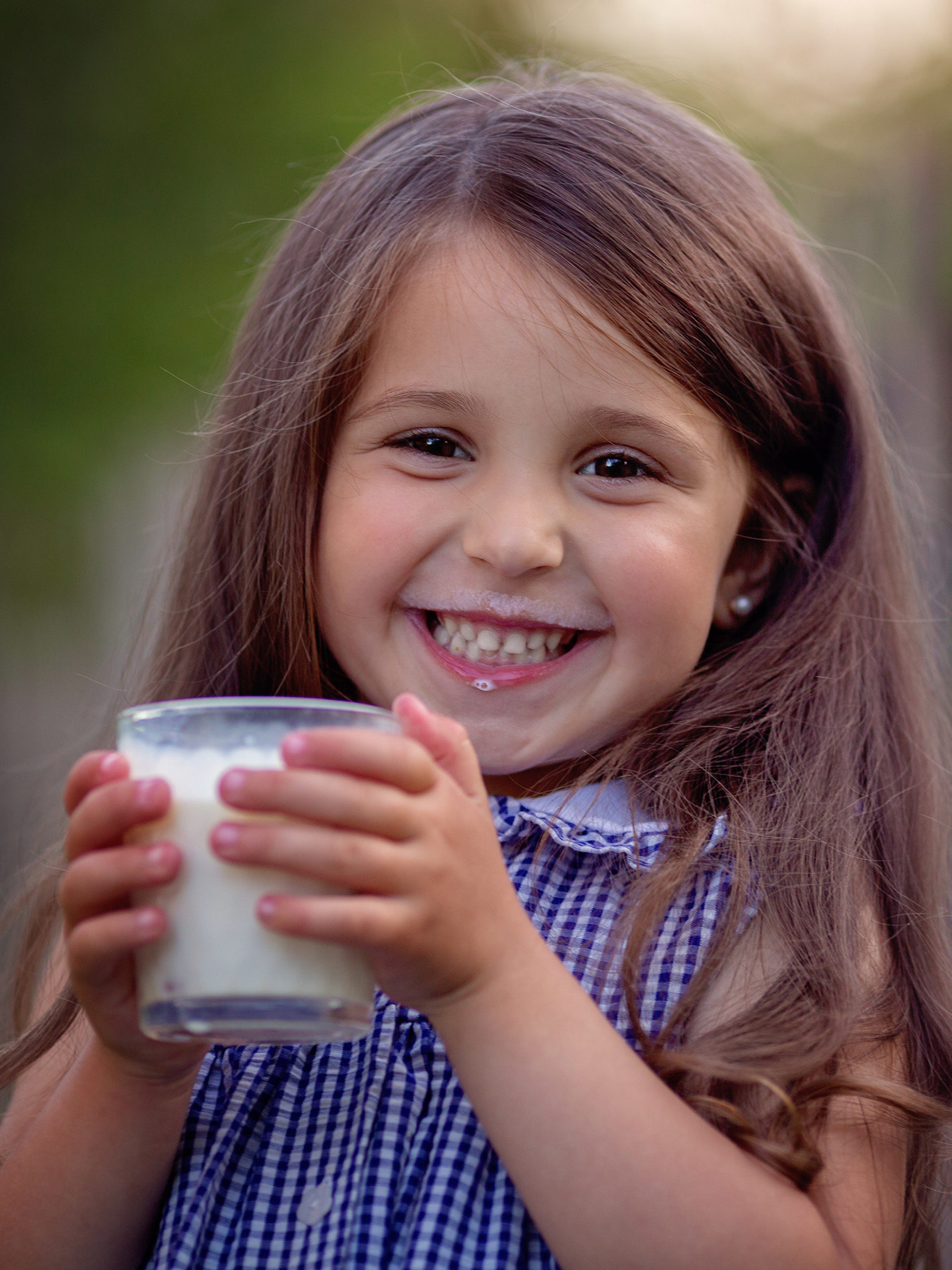little girl smiling and drinking a glass of milk
