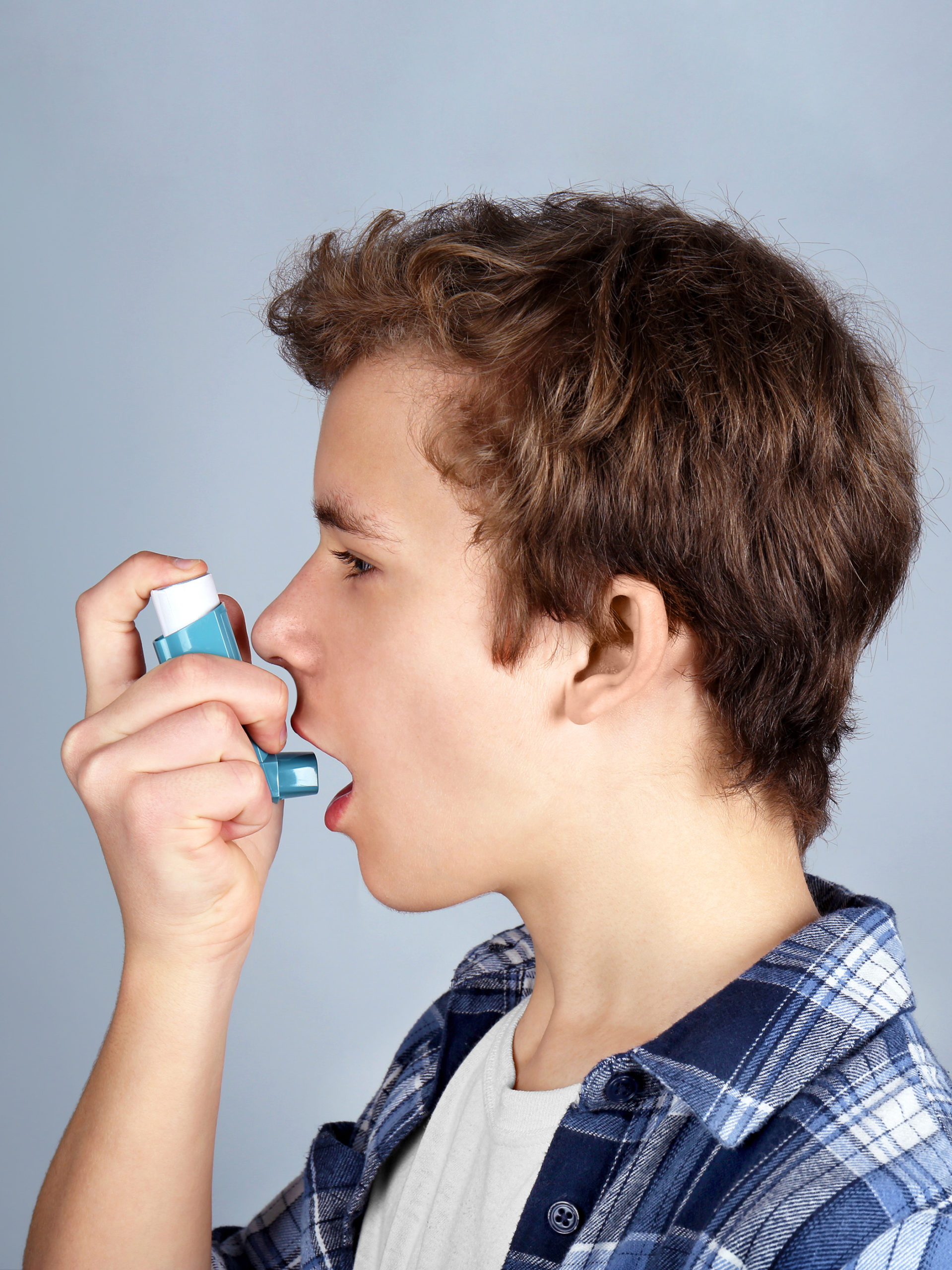 Young boy using inhaler for asthma and respiratory issues