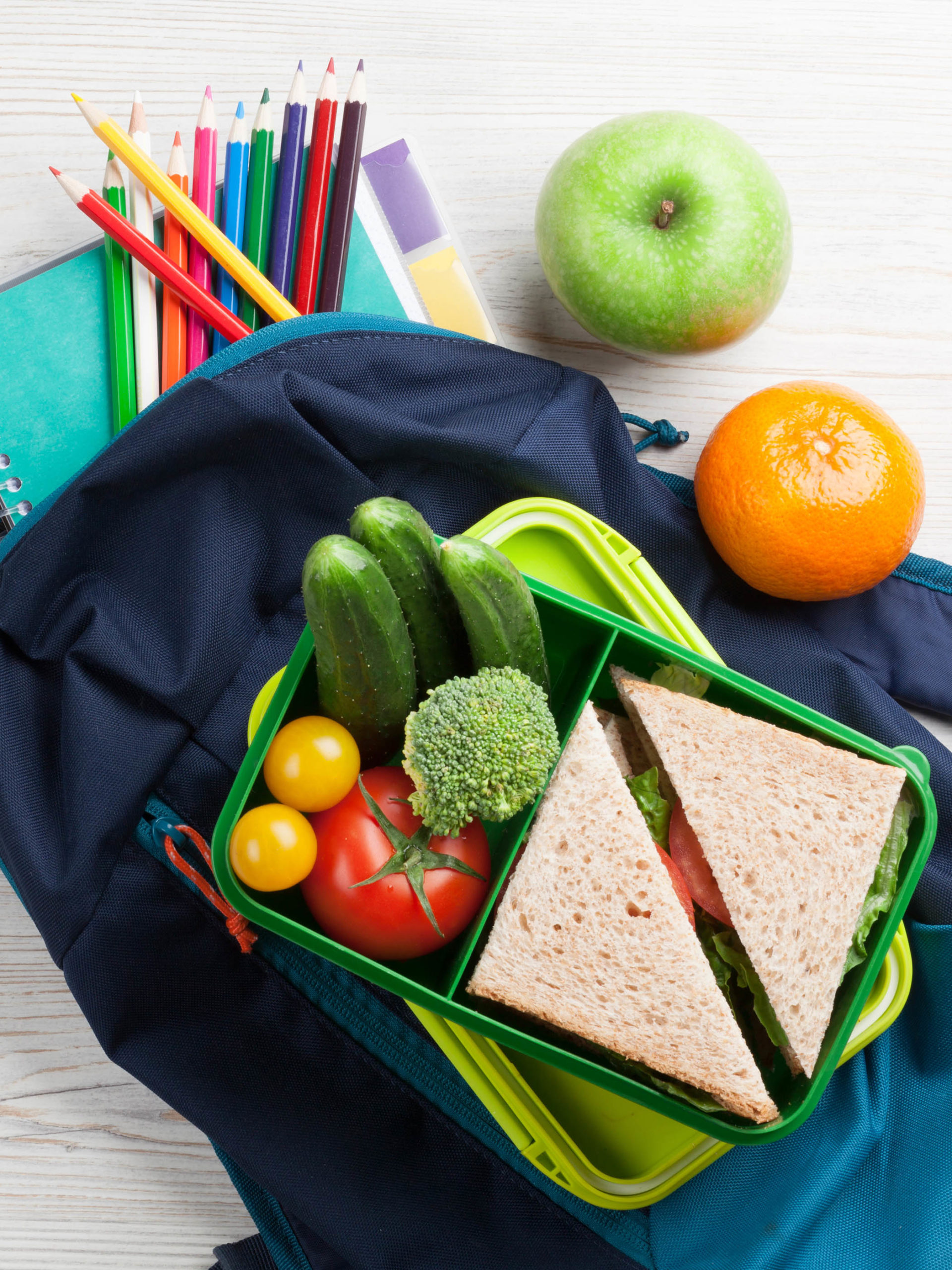 Lunch box with vegetables and sandwich on wooden table