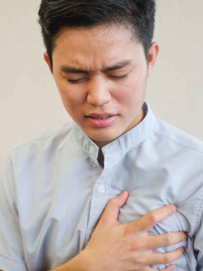 young man clutching his hand to his chest in pain