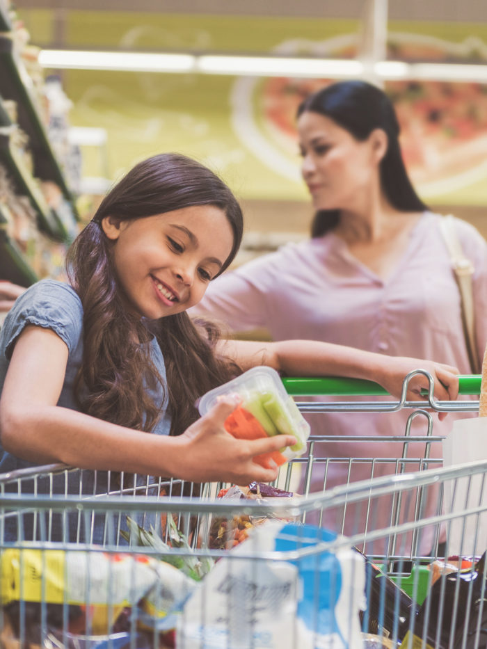 girl looking at nutrition facts on snack package of carrots and celery