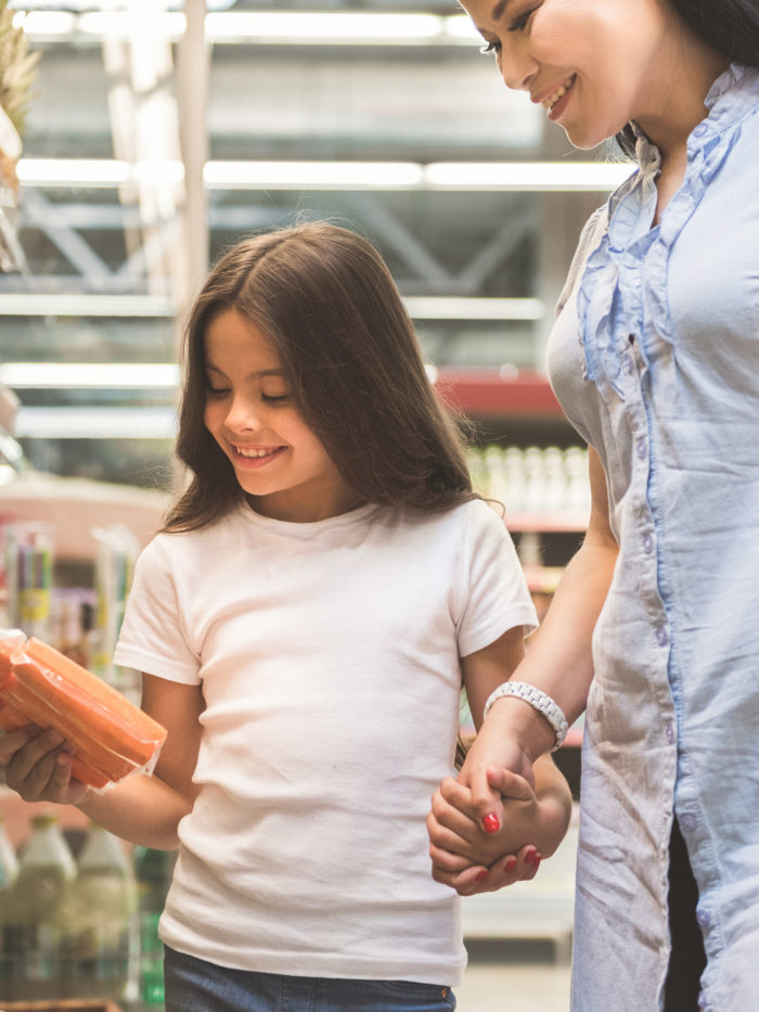 girl and her mother shopping for food, checking nutrition information