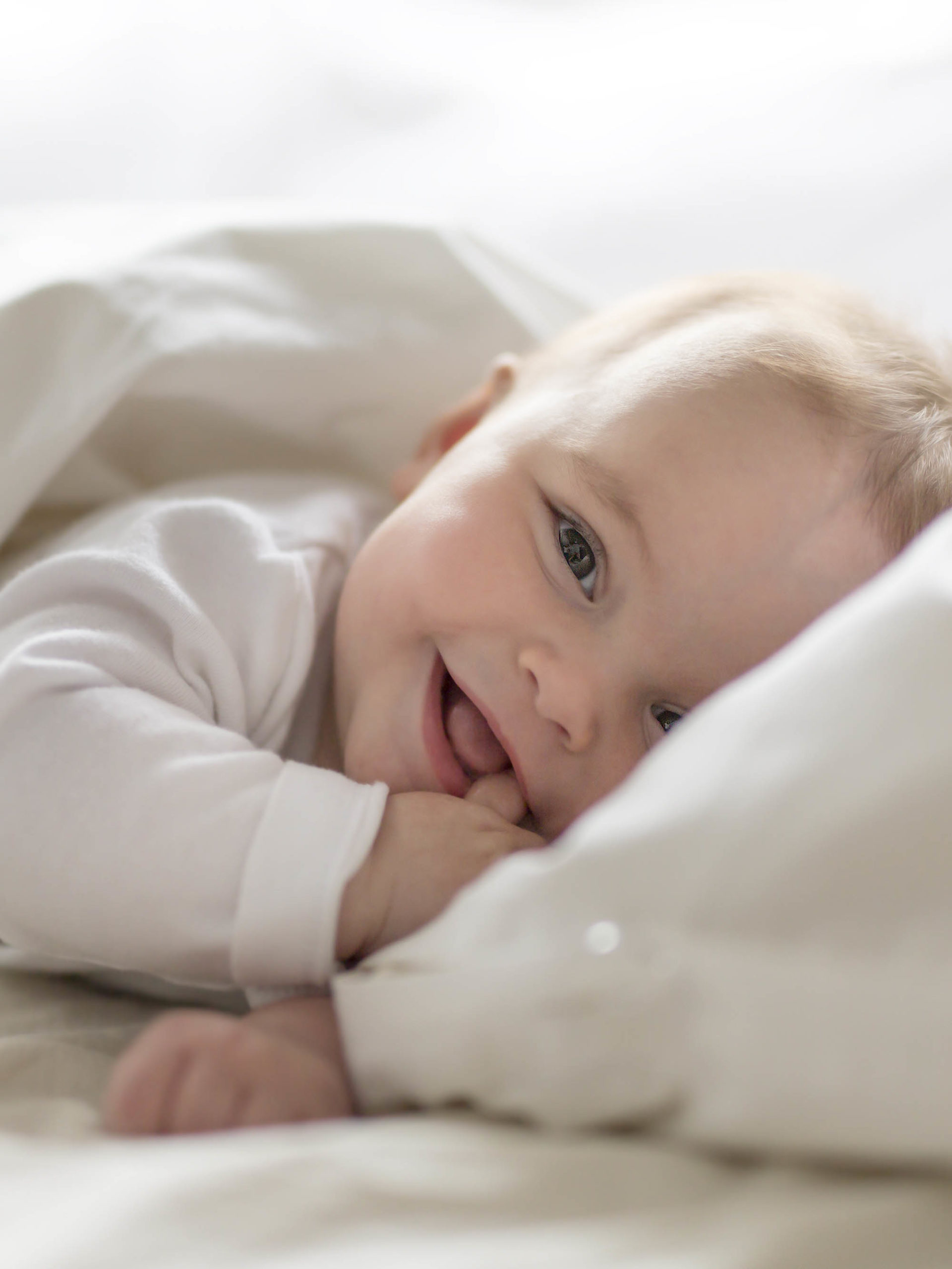 smiling baby girl nestled in bed after waking up from nap