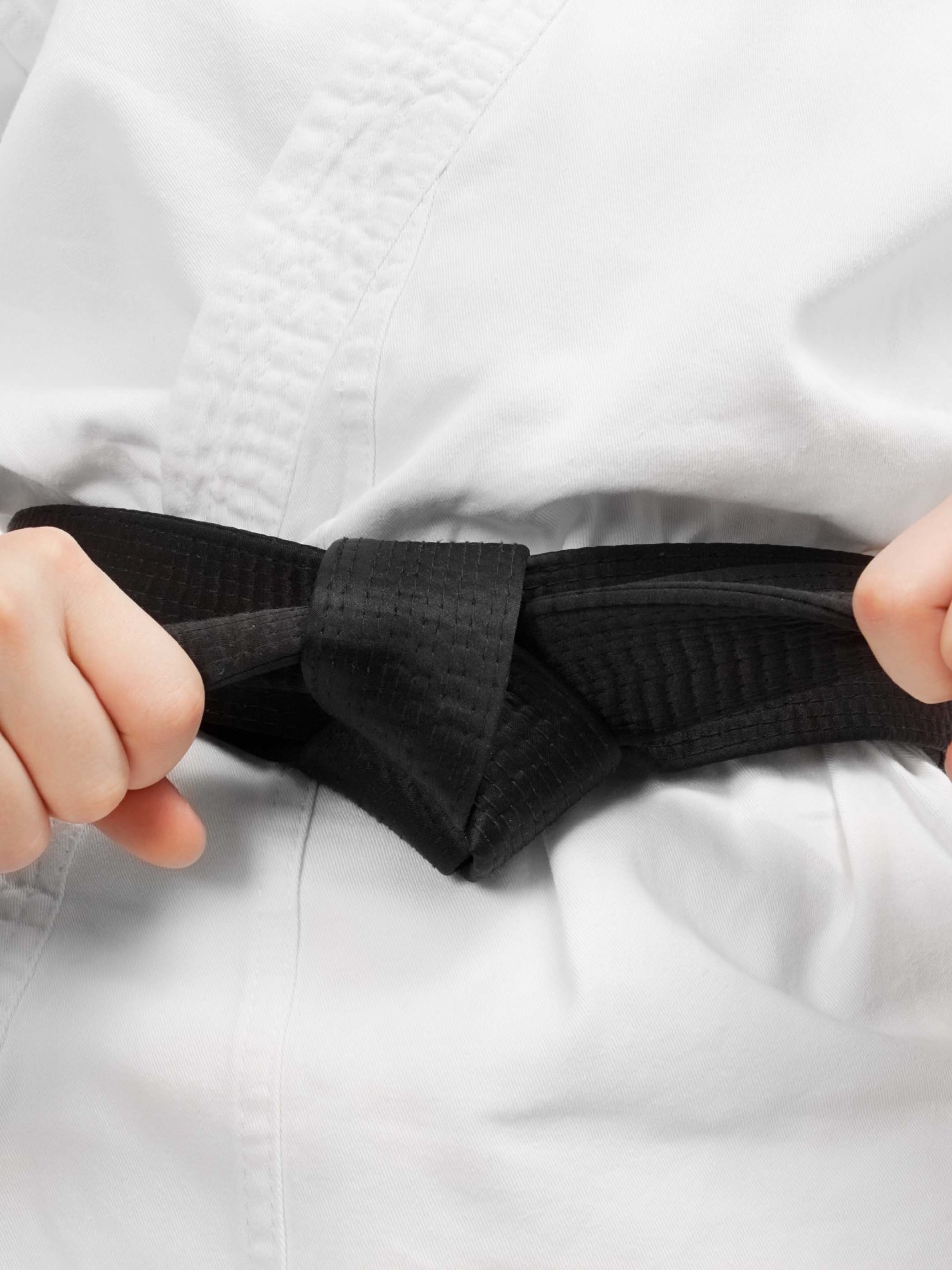 Martial arts boy tying the knot to his black belt