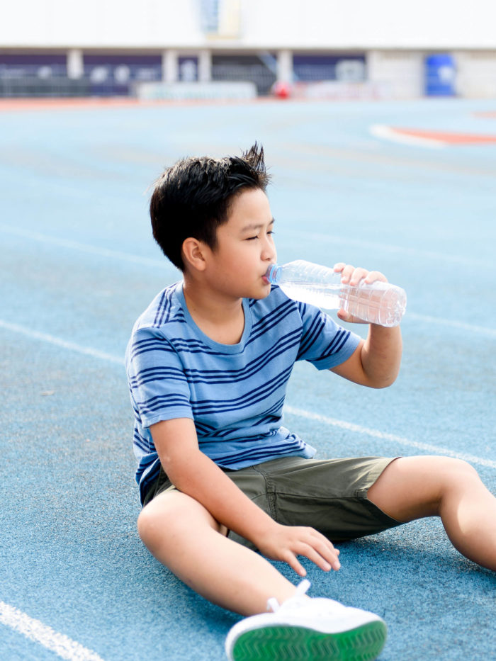 oy drinking water from bottle during resting after running
