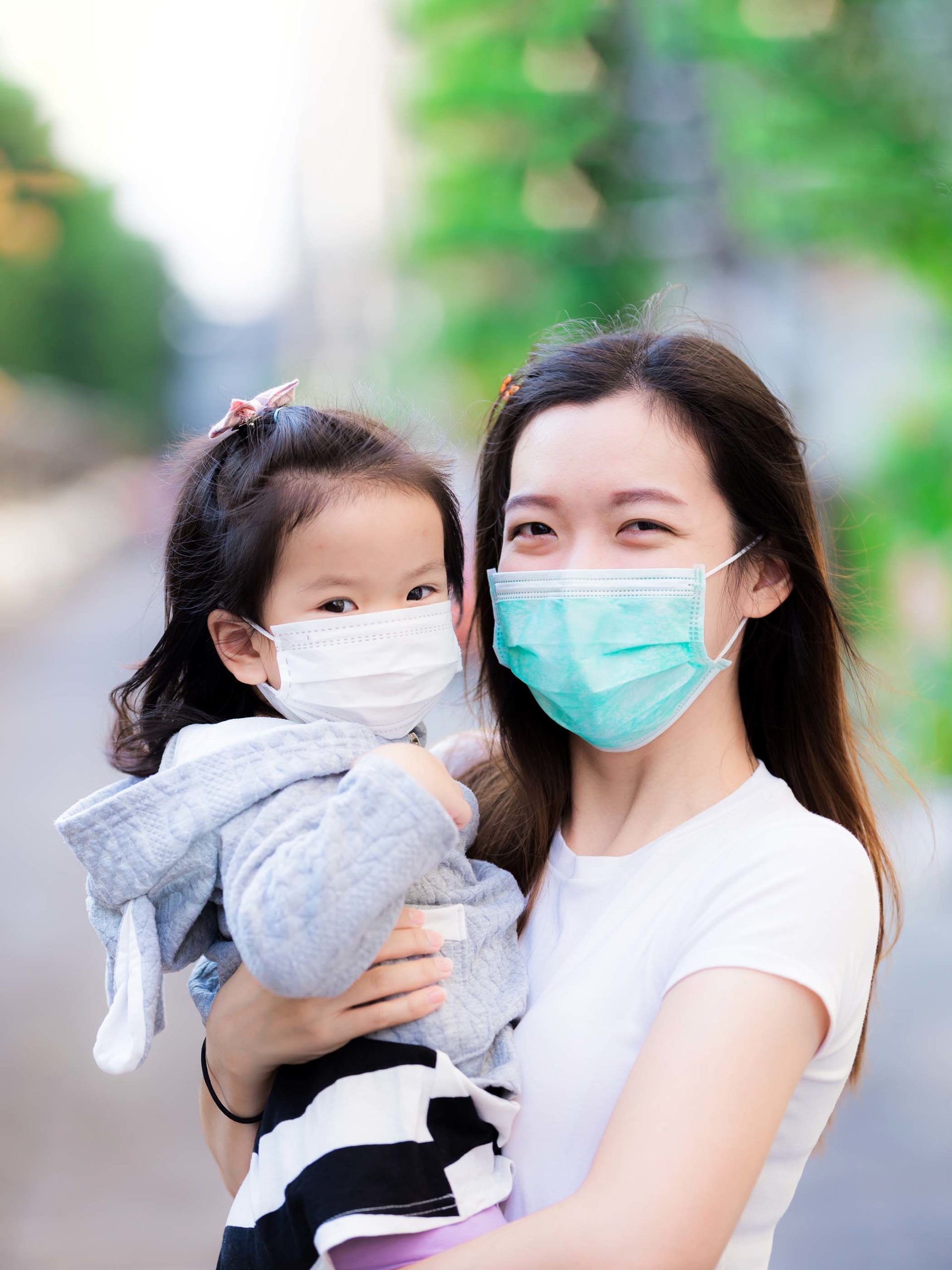 Mom and her daughter smiling outside with masks on