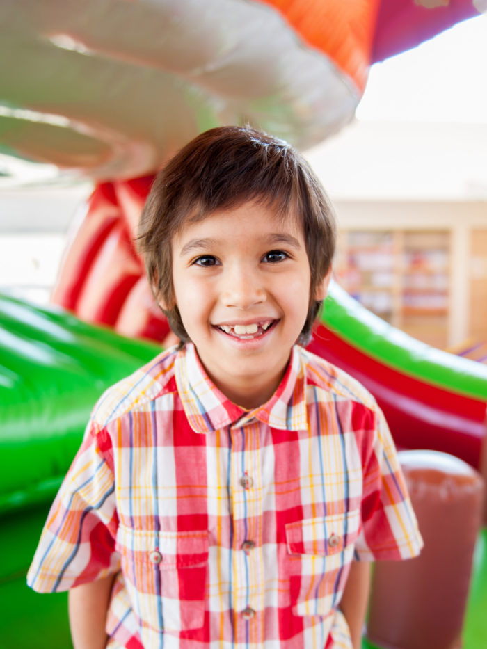 Boy smiles in front of inflatable bounce house