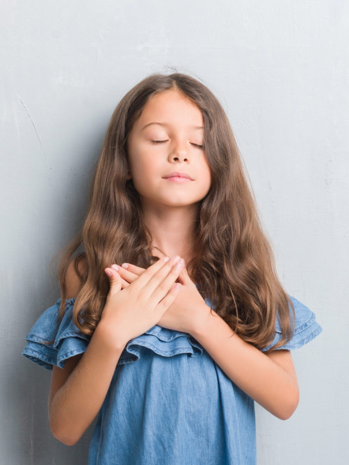 girl with eyes closed and hands on her chest taking in a deep breath