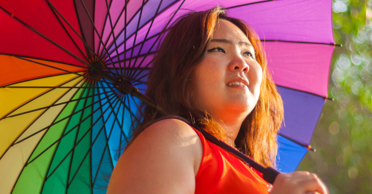 girl smiles holding rainbow umbrella