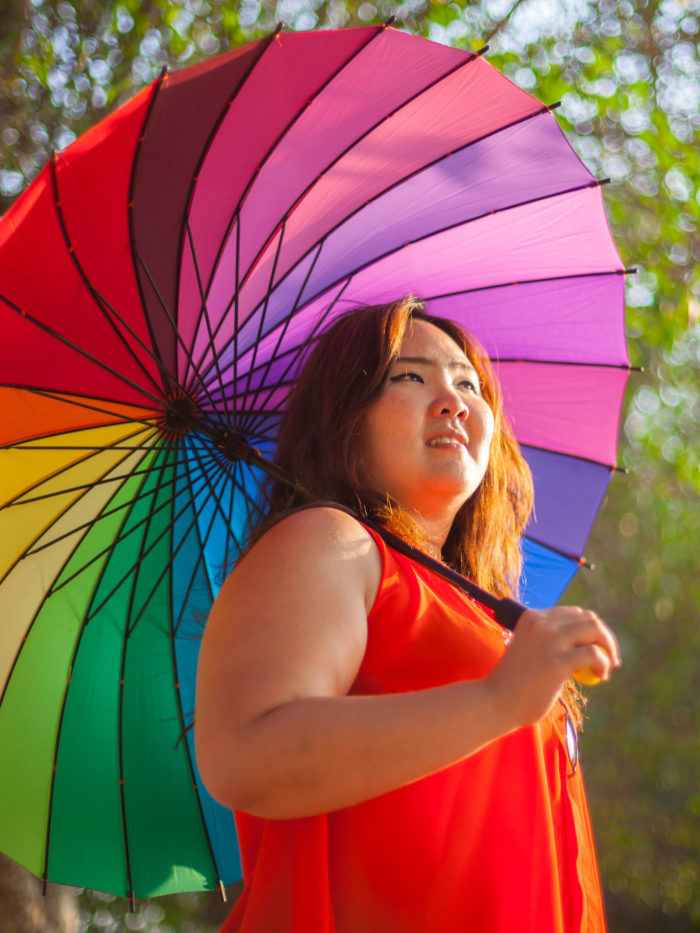 girl smiles holding rainbow umbrella