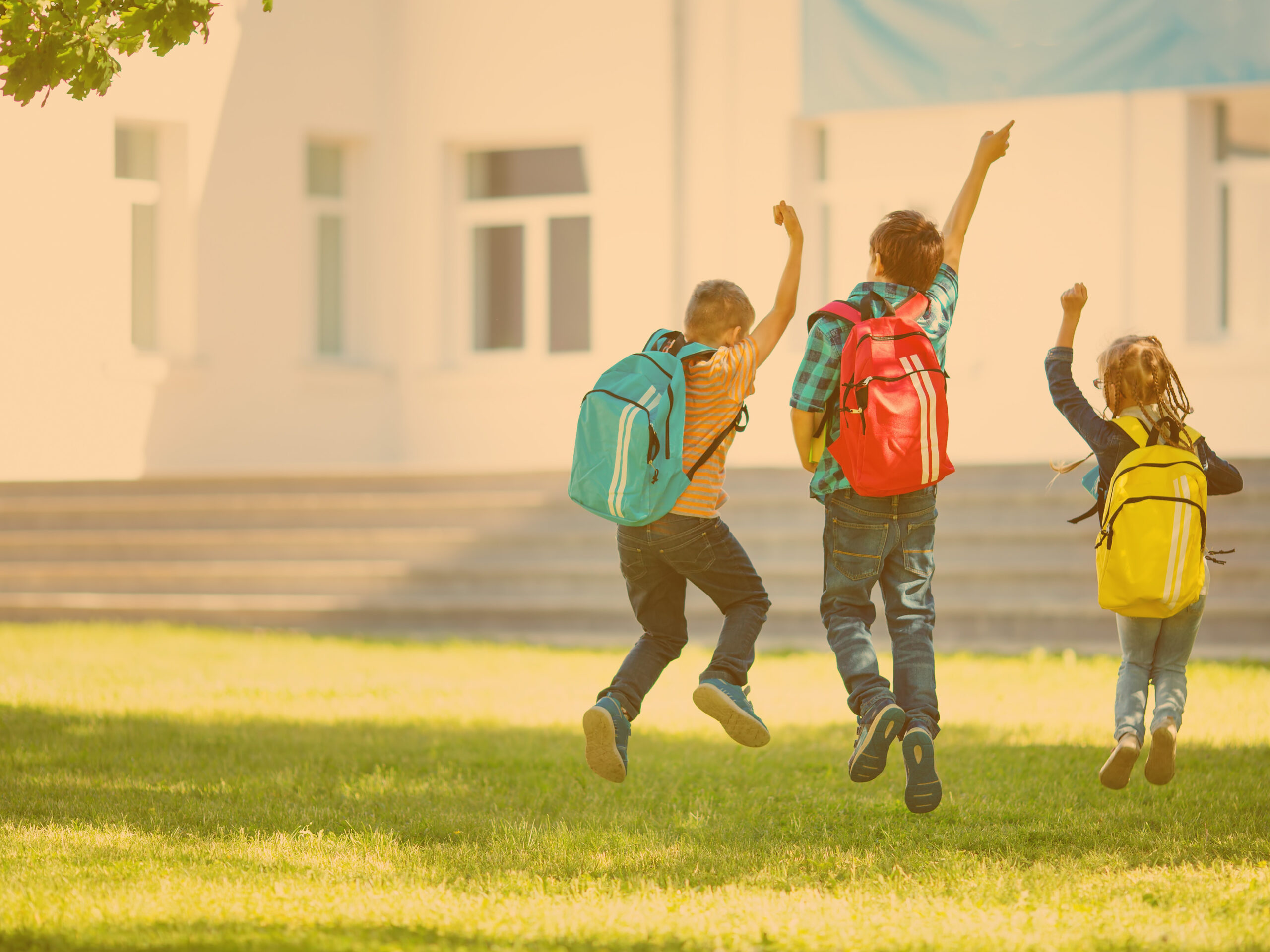 image of kids wearing backpacks jumping in the air, taken from behind