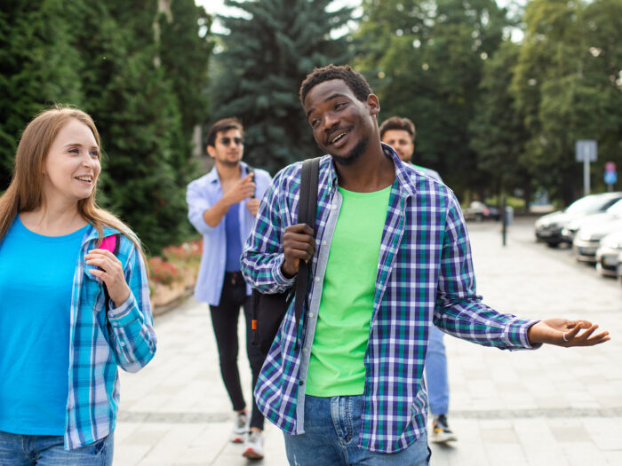 college student walks with friends while shrugging