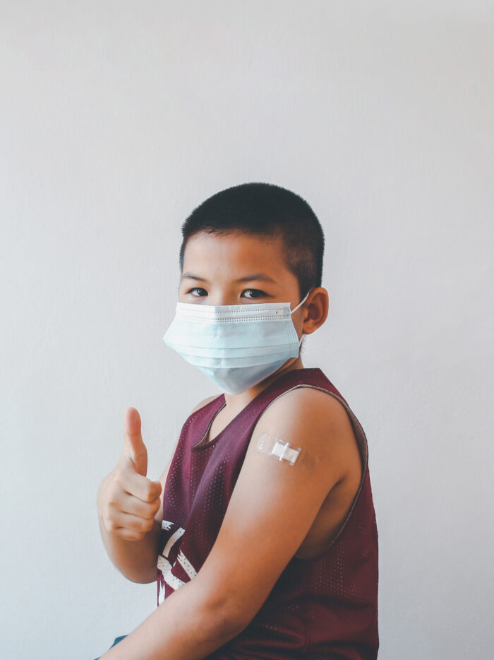 young child gives thumbs up after getting a flu shot