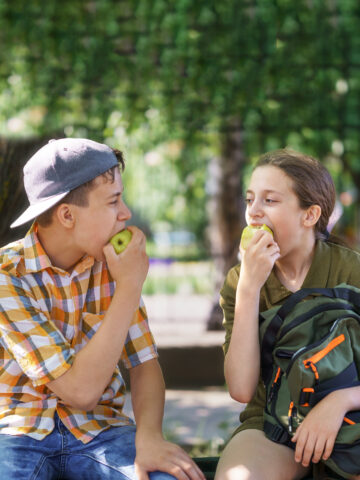Kids look at each other while eating apples