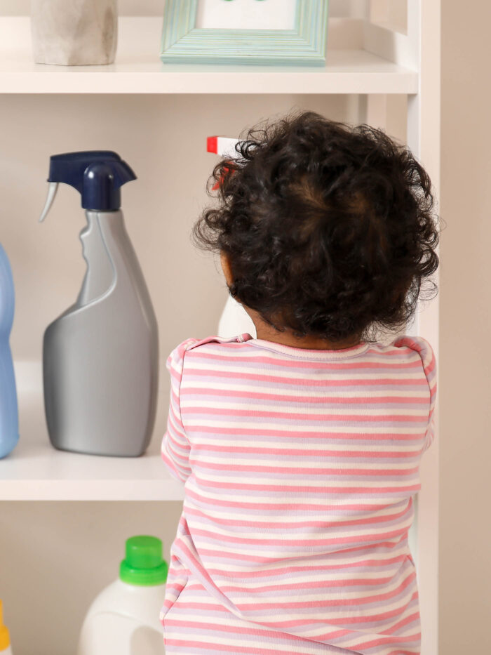 Child looks in cabinet with cleaning supplies