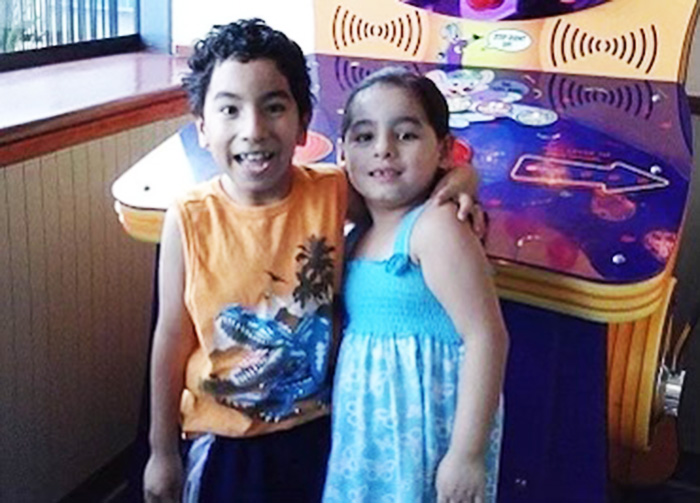 Siblings Hector and Elizabeth as young children smile together at Chuck E Cheese 