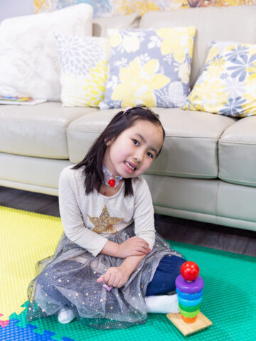 CHOC patient Kaslyn sits on a floor mat with toys following her miraculous recovery from heart and brain surgery