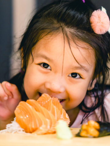 Child smiles with salmon sushi