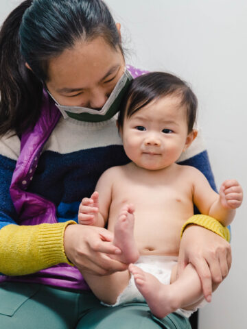 Baby smiles and looks into camera with parent looking at them. Baby exams for newborns at hospital: From a CHOC pediatrician