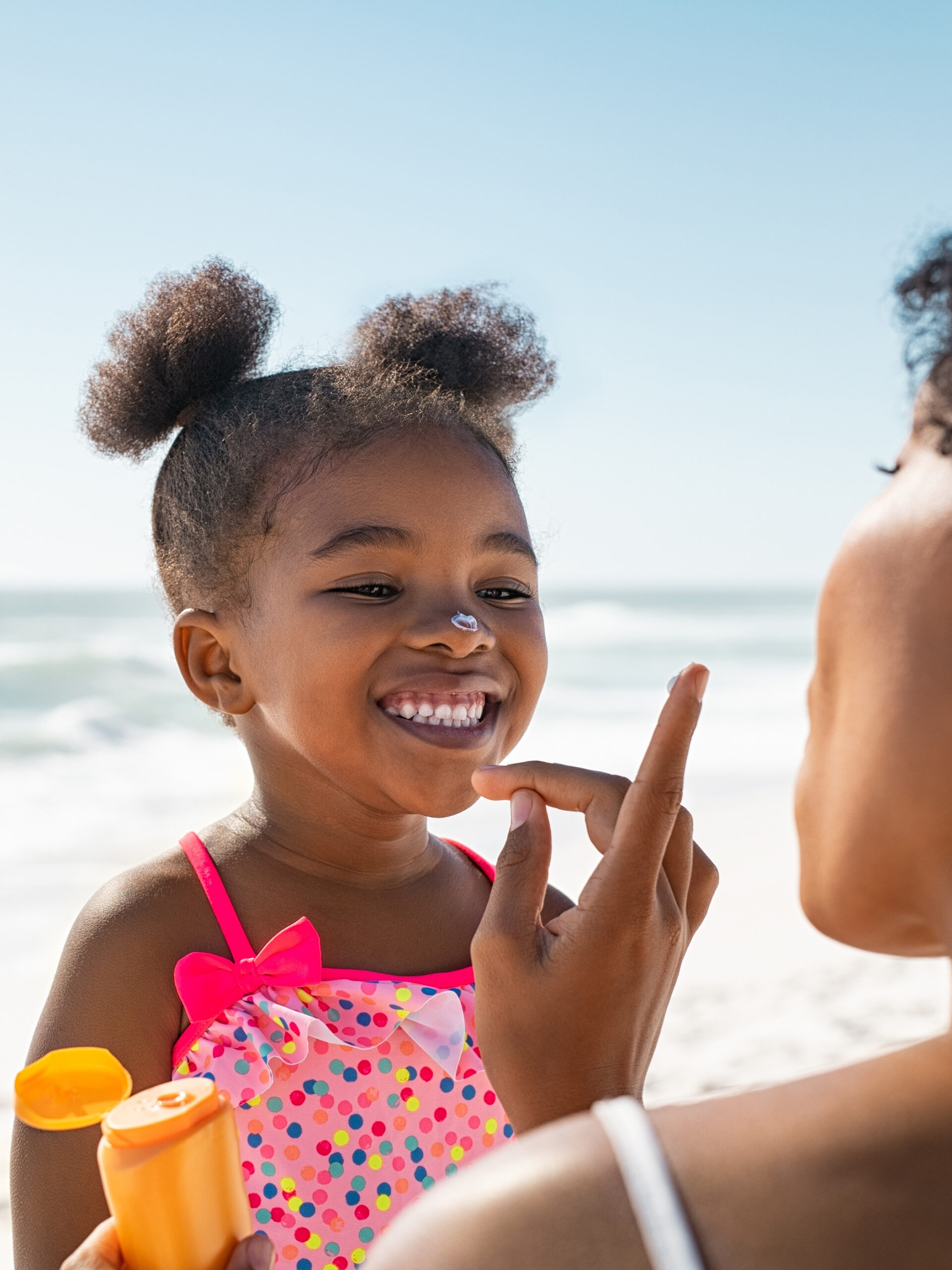 parent puts sunscreen on child at the beach - sun allergies and other skin reactions to the sun in kids. Tips to avoid skin-related reactions to the sun in kids.