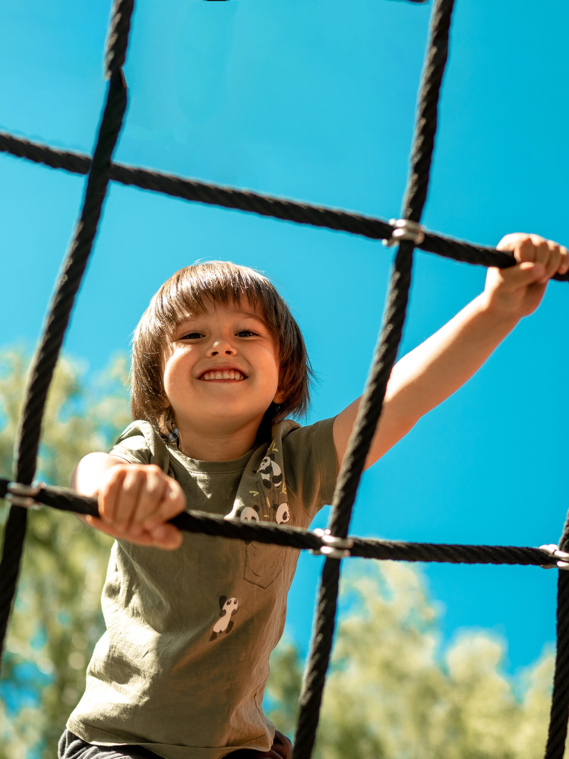 Child plays on jungle gym and smiles - 5 ways to keep kids cool during hot summer weather
