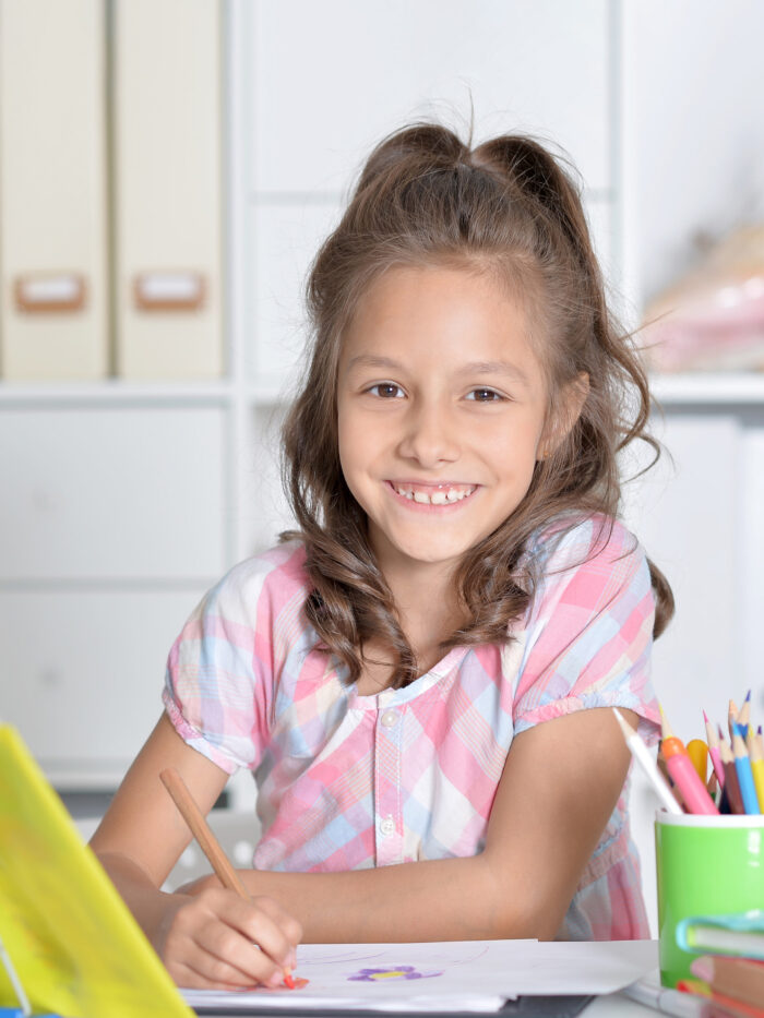 Child looks to camera and smiles while in classroom