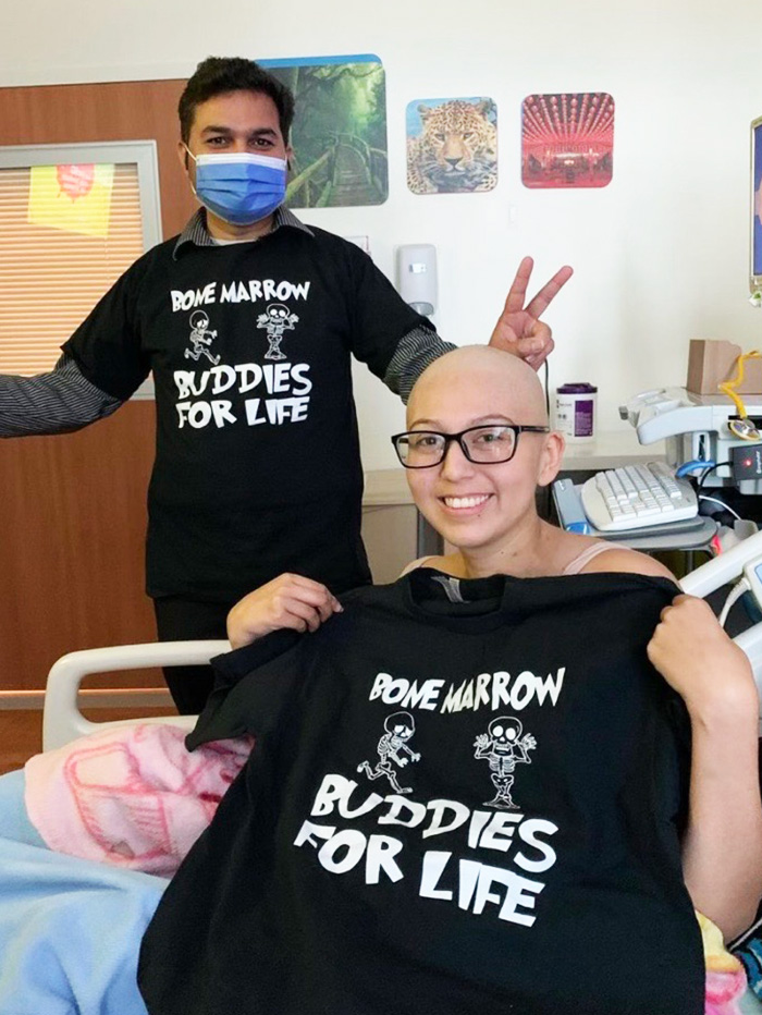 Dr. Chavan gives peace signs while wearing a "bone marrow buddies for life" shirt that matches Eliza 