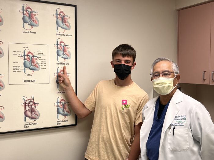 John points at coarctation of the aorta while standing next to Dr. Palafox - both wearing masks