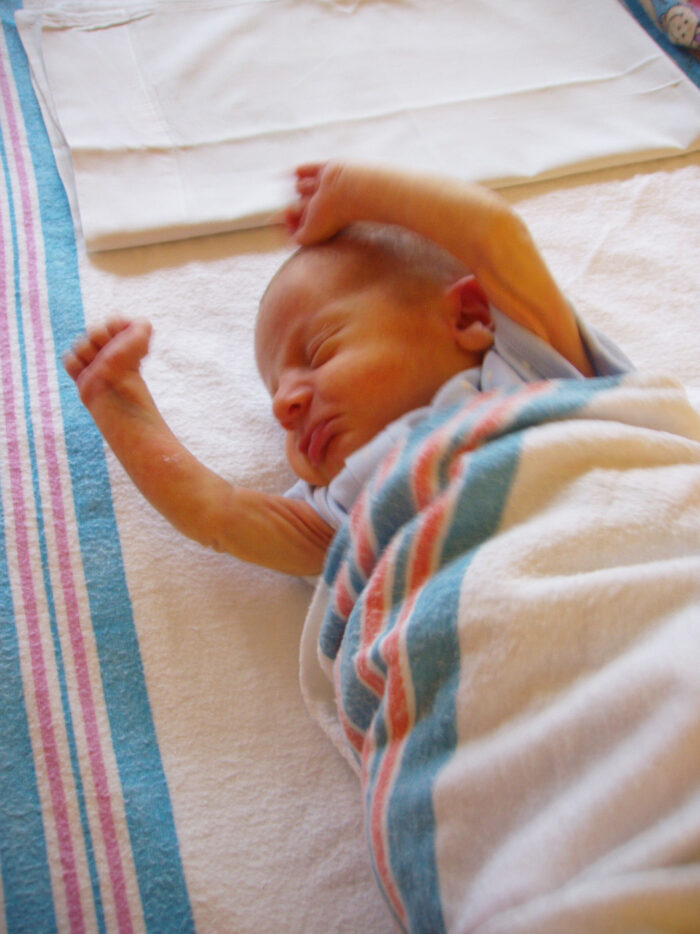 Baby in blanket with arms raised 