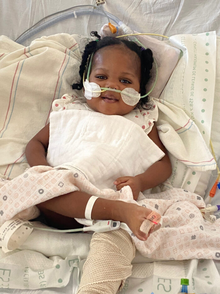 Little girl looks and smiles with wires following a life-saving heart transplant