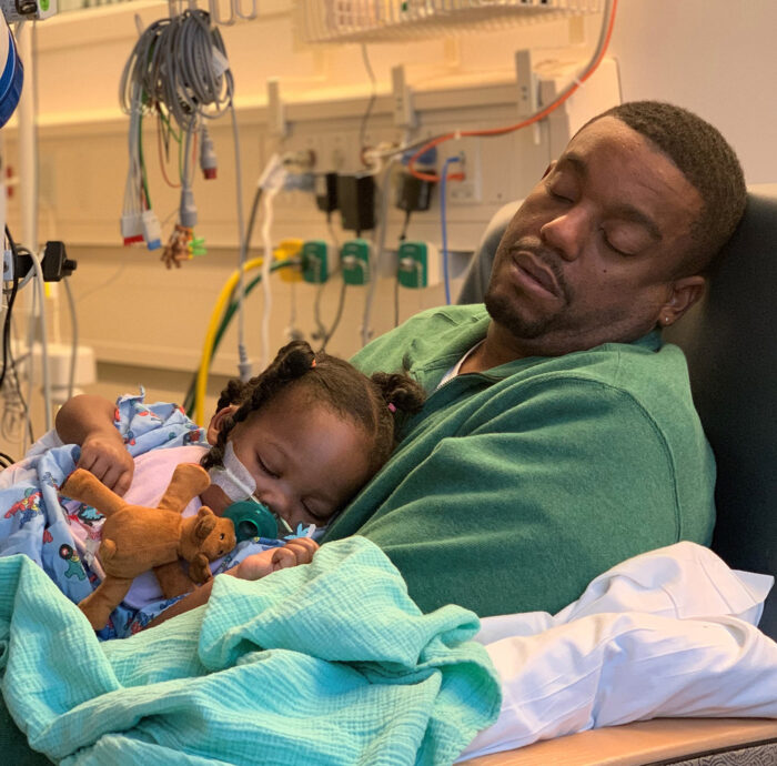 CHOC heart patient Olivia and her dad rest during a hospital stay 