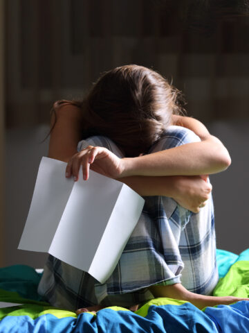 Teen crying while holding piece of paper - how to help teens cope with college rejections