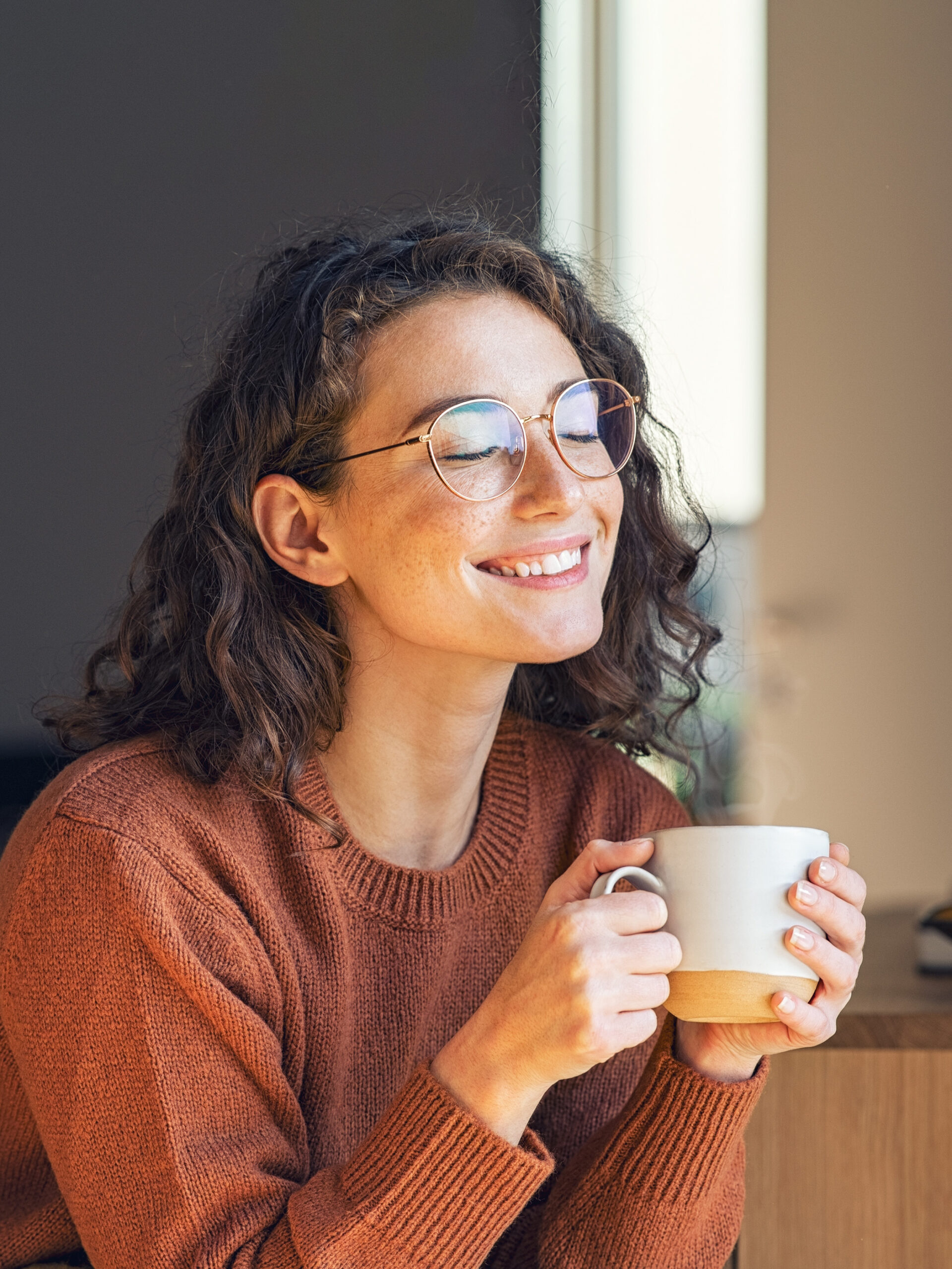 Woman smiles while drinking coffee - self-care strategies for parents and caregivers