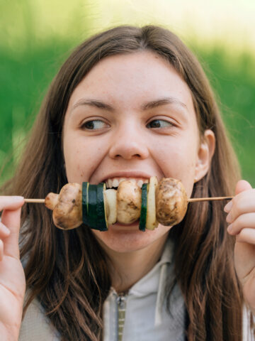 Teen eating kebab while smiling