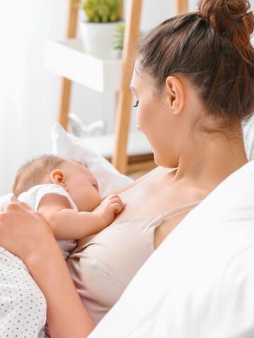 A woman with brown hair breastfeeds her baby